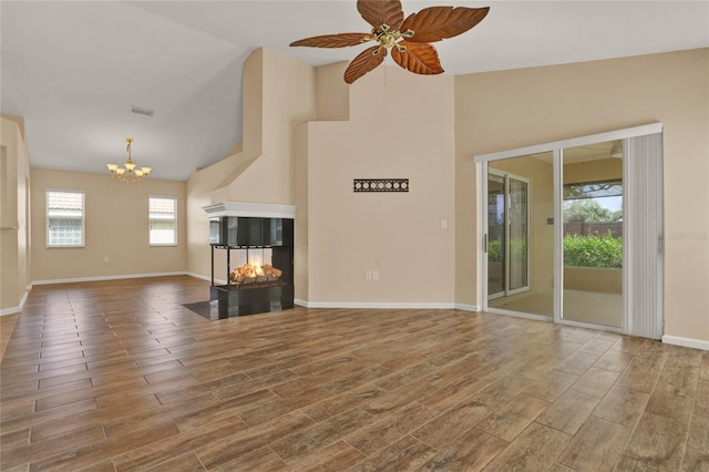 unfurnished living room with baseboards, visible vents, wood finished floors, a multi sided fireplace, and ceiling fan with notable chandelier