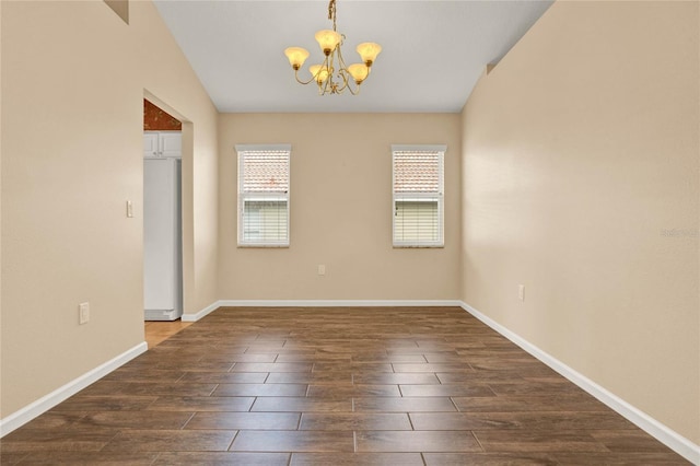 unfurnished room featuring lofted ceiling, dark wood-style flooring, baseboards, and a notable chandelier