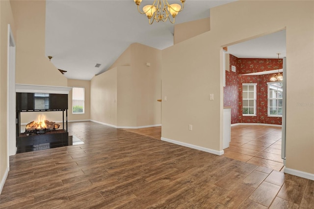 unfurnished living room featuring wallpapered walls, baseboards, wood finished floors, an inviting chandelier, and a multi sided fireplace