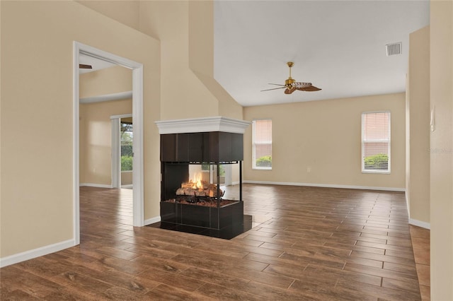 living area with dark wood-type flooring, a fireplace, a ceiling fan, and baseboards