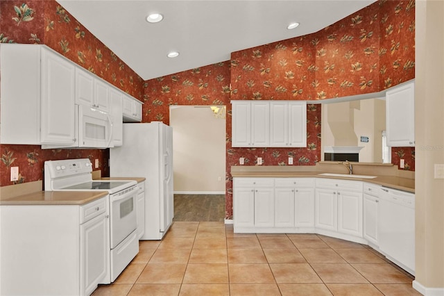 kitchen with white appliances, wallpapered walls, lofted ceiling, light countertops, and a sink