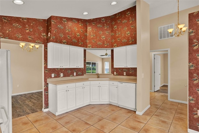 kitchen with light countertops, visible vents, a sink, white appliances, and wallpapered walls