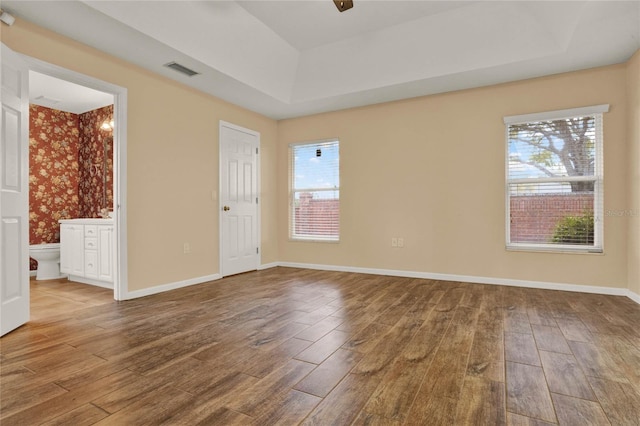 unfurnished room with a wealth of natural light, wood finished floors, and visible vents