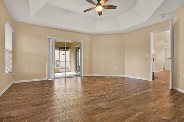 unfurnished room with a ceiling fan, a raised ceiling, baseboards, and dark wood-style flooring