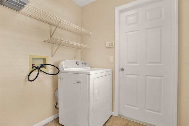 clothes washing area with washer / dryer, laundry area, baseboards, and light tile patterned floors