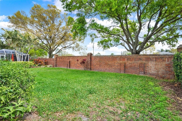 view of yard with glass enclosure and a fenced backyard