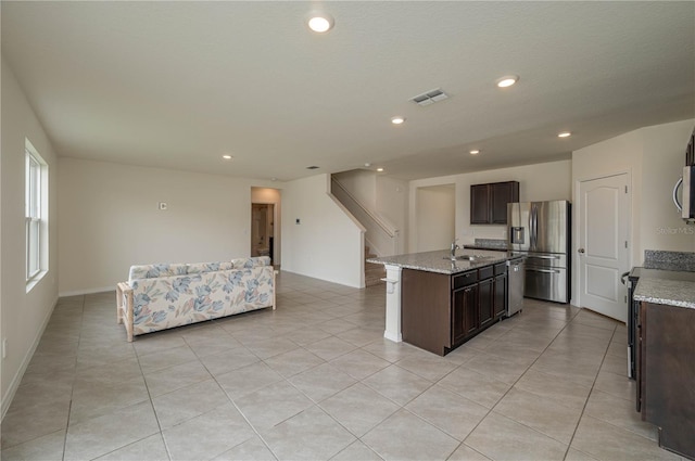 kitchen featuring dark brown cabinets, a kitchen island with sink, stainless steel appliances, and a sink