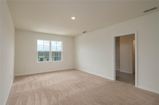 spare room featuring baseboards, recessed lighting, visible vents, and light colored carpet