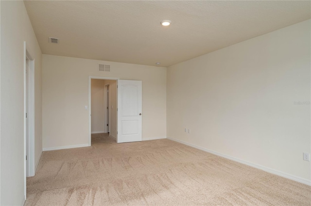 empty room with baseboards, visible vents, and light colored carpet