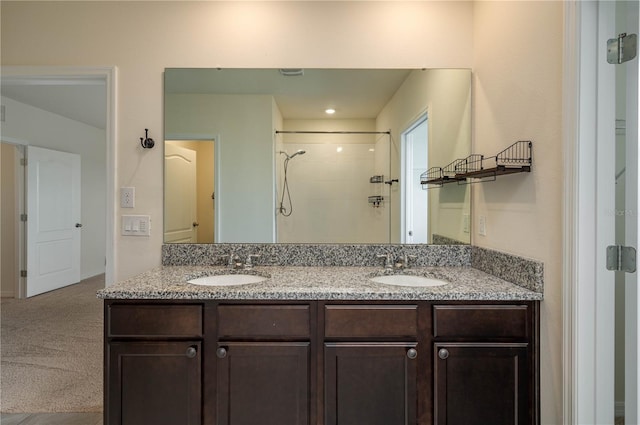 bathroom featuring double vanity, a tile shower, and a sink