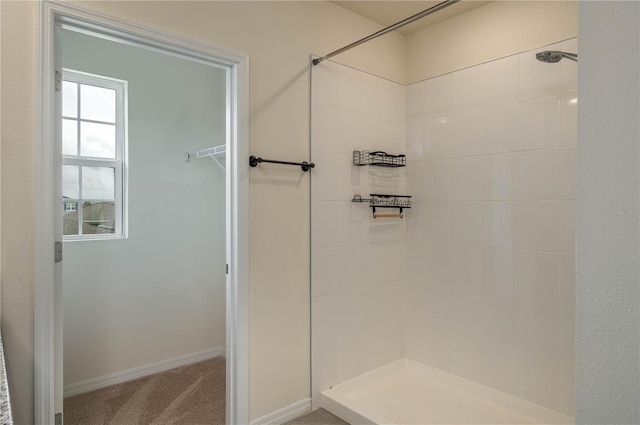 bathroom with tiled shower and baseboards