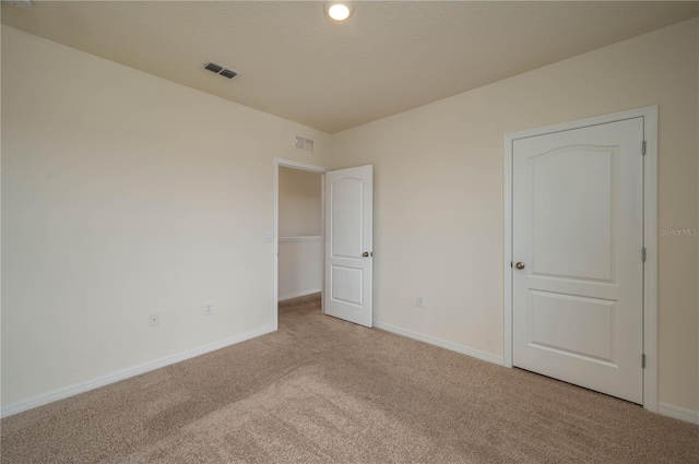 unfurnished bedroom with baseboards, visible vents, and light colored carpet