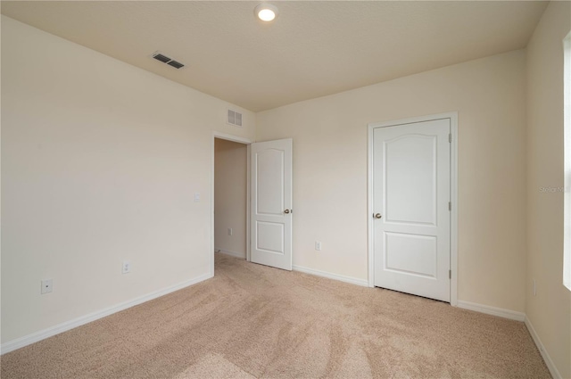 unfurnished bedroom with light carpet, visible vents, and baseboards