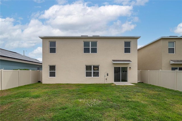 back of house with a fenced backyard, a yard, and stucco siding