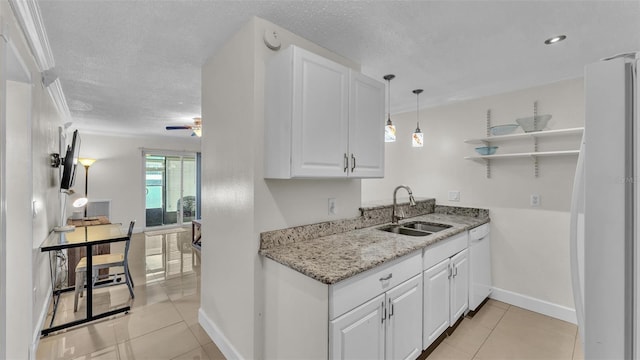 kitchen featuring a textured ceiling, light tile patterned flooring, white appliances, a sink, and white cabinetry