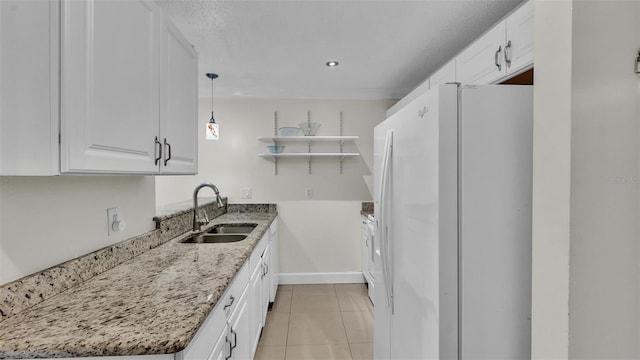 kitchen featuring light tile patterned floors, freestanding refrigerator, white cabinetry, open shelves, and a sink