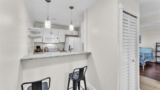 kitchen with light stone counters, decorative light fixtures, a kitchen breakfast bar, white appliances, and baseboards