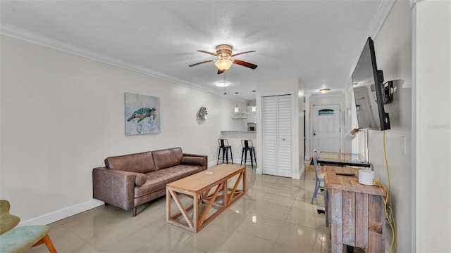 living area featuring baseboards, ceiling fan, and crown molding