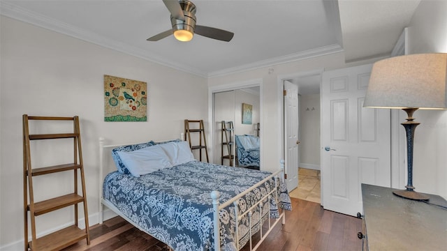 bedroom featuring a closet, ornamental molding, ceiling fan, wood finished floors, and baseboards