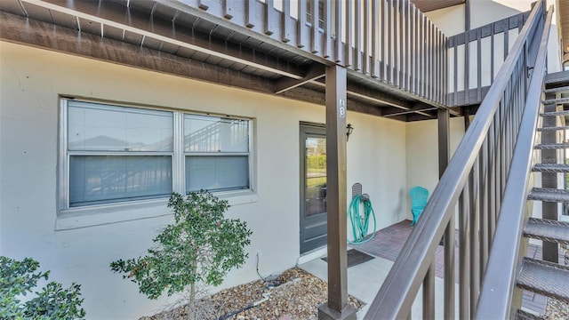 view of exterior entry with a balcony and stucco siding