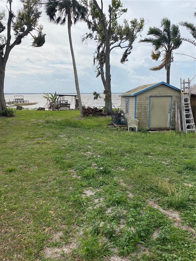 view of yard featuring a water view, a storage unit, and an outbuilding