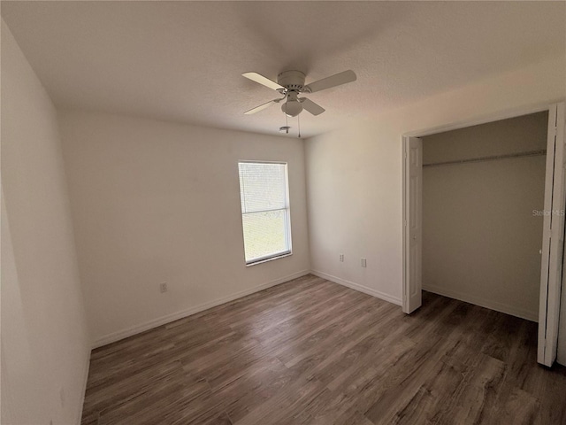 unfurnished bedroom featuring a closet, a ceiling fan, a textured ceiling, wood finished floors, and baseboards