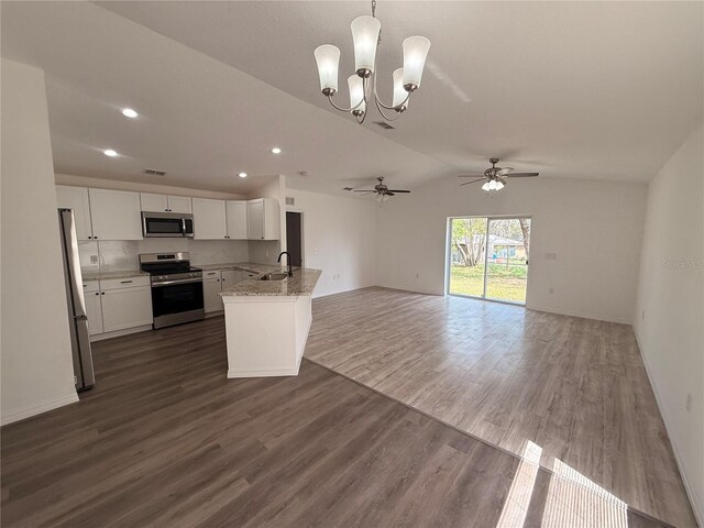 kitchen featuring light stone counters, white cabinetry, open floor plan, appliances with stainless steel finishes, and dark wood finished floors