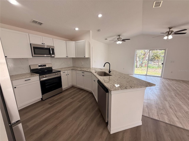 kitchen featuring lofted ceiling, stainless steel appliances, a peninsula, a sink, and visible vents