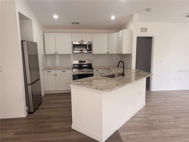 kitchen featuring visible vents, light stone counters, a peninsula, stainless steel appliances, and a sink