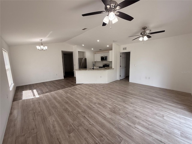 unfurnished living room with visible vents, vaulted ceiling, a sink, and wood finished floors