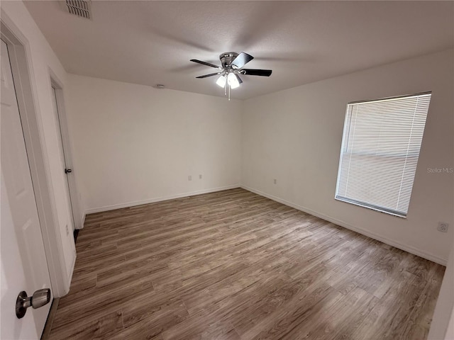 spare room with visible vents, ceiling fan, baseboards, and wood finished floors