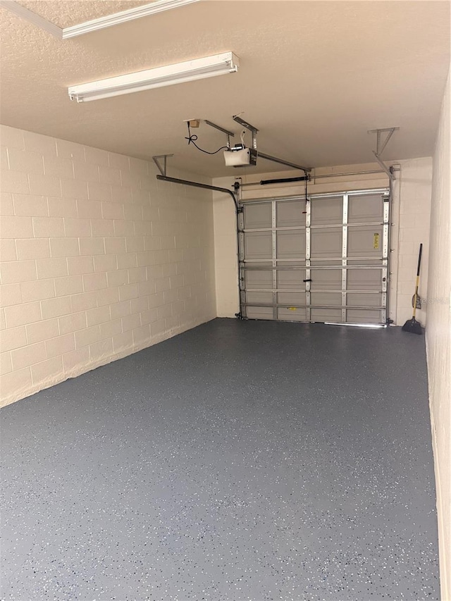 garage with concrete block wall and a garage door opener