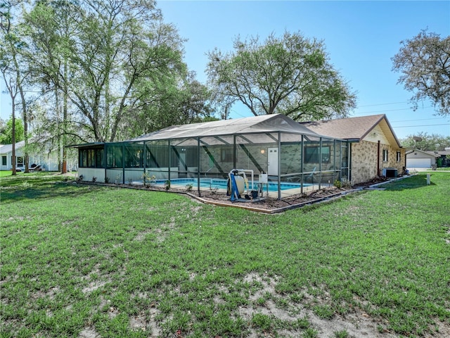 rear view of property featuring an outdoor pool, a lanai, and a yard