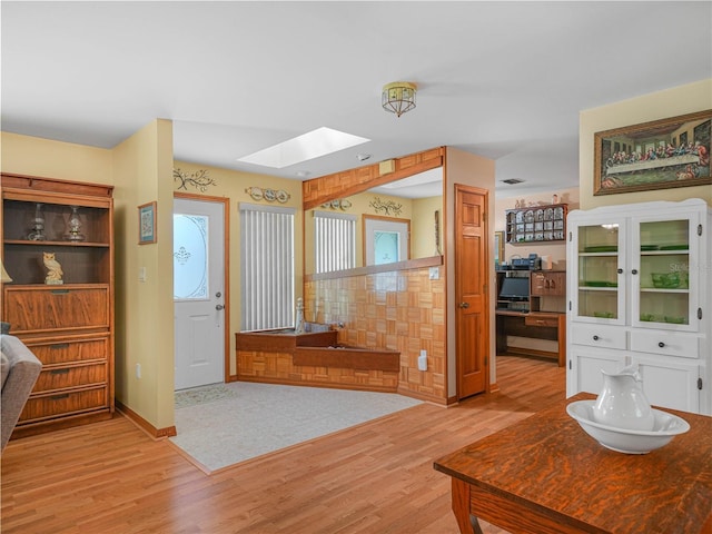 interior space with a skylight, baseboards, and wood finished floors