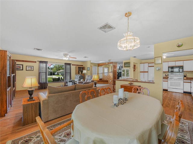 dining room featuring ceiling fan, visible vents, and wood finished floors