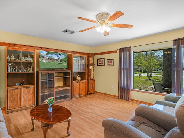 living area featuring light wood-type flooring, baseboards, visible vents, and a ceiling fan