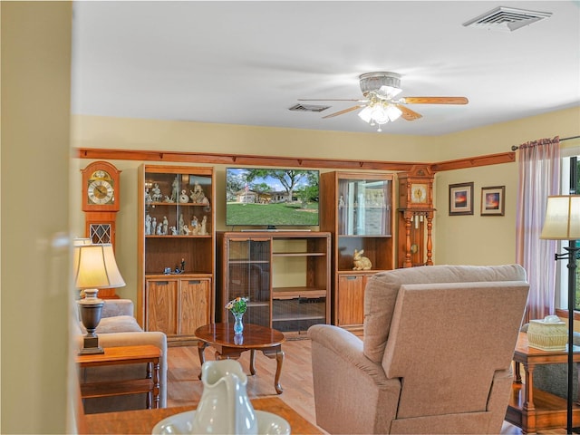 living area featuring visible vents, a ceiling fan, and wood finished floors