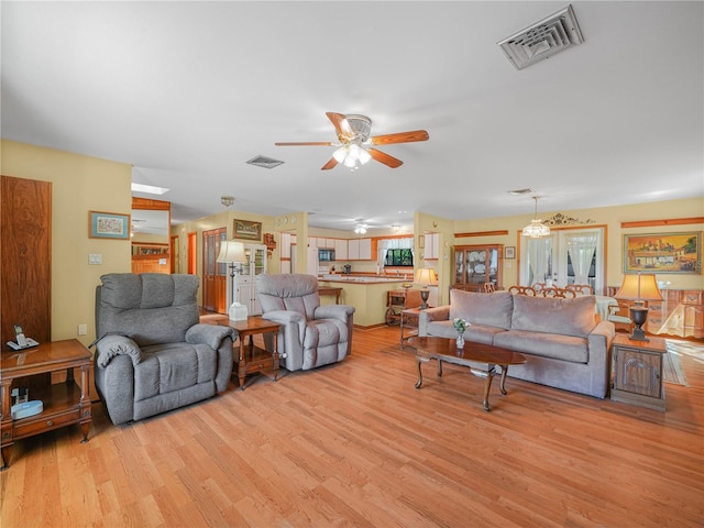 living room with light wood-style flooring, visible vents, and a ceiling fan