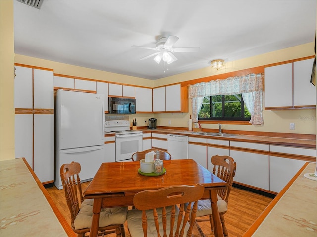 kitchen with white appliances, white cabinets, a sink, and light wood-style flooring