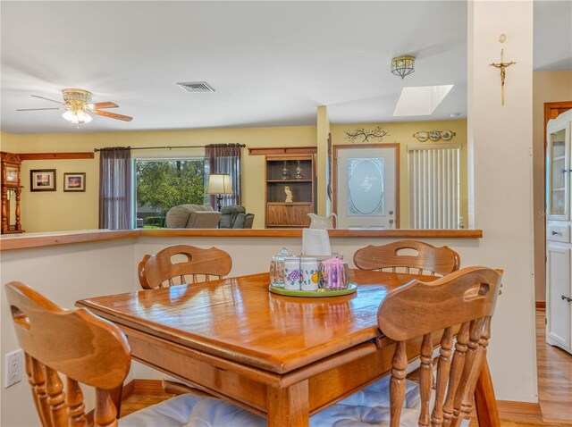 dining room featuring a skylight, baseboards, visible vents, and a ceiling fan