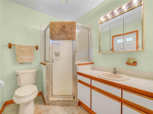 bathroom with tile patterned flooring, toilet, vanity, baseboards, and a stall shower