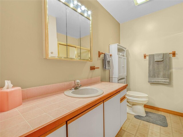 bathroom with baseboards, vanity, toilet, and tile patterned floors