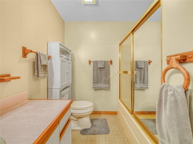 full bathroom featuring tile patterned flooring, toilet, bath / shower combo with glass door, vanity, and baseboards