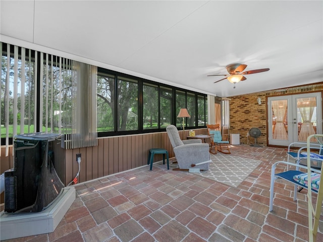 sunroom / solarium with a wood stove, ceiling fan, and french doors