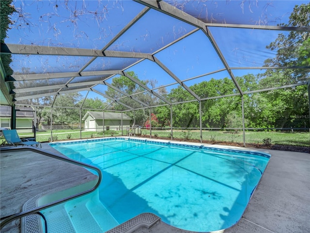 pool with a patio area, glass enclosure, and an outdoor structure