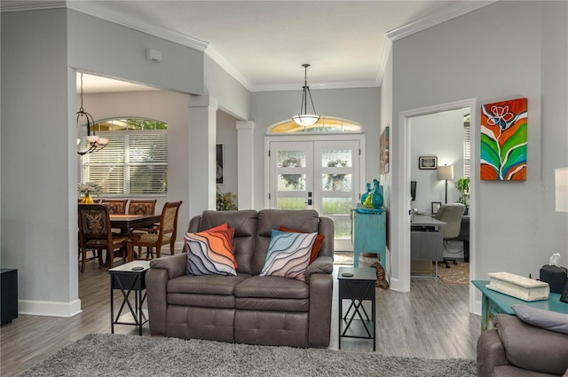 living area featuring baseboards, ornamental molding, french doors, an inviting chandelier, and wood finished floors