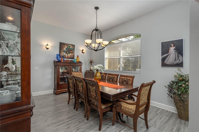 dining area featuring baseboards, an inviting chandelier, and wood finished floors