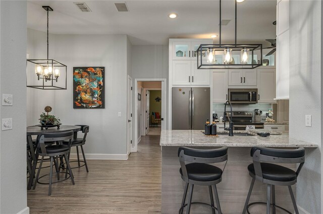 kitchen featuring wood finished floors, light stone countertops, visible vents, and stainless steel appliances