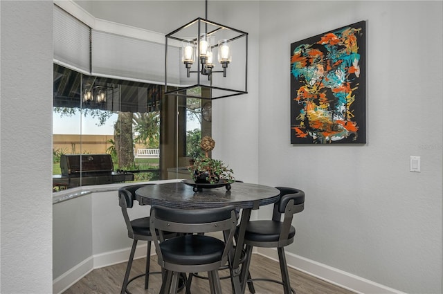 dining area with a notable chandelier, baseboards, and wood finished floors