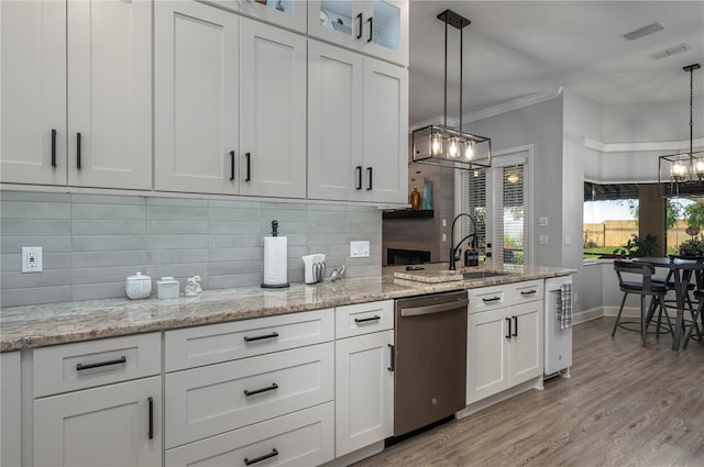 kitchen with ornamental molding, decorative backsplash, white cabinets, light wood-style floors, and stainless steel dishwasher